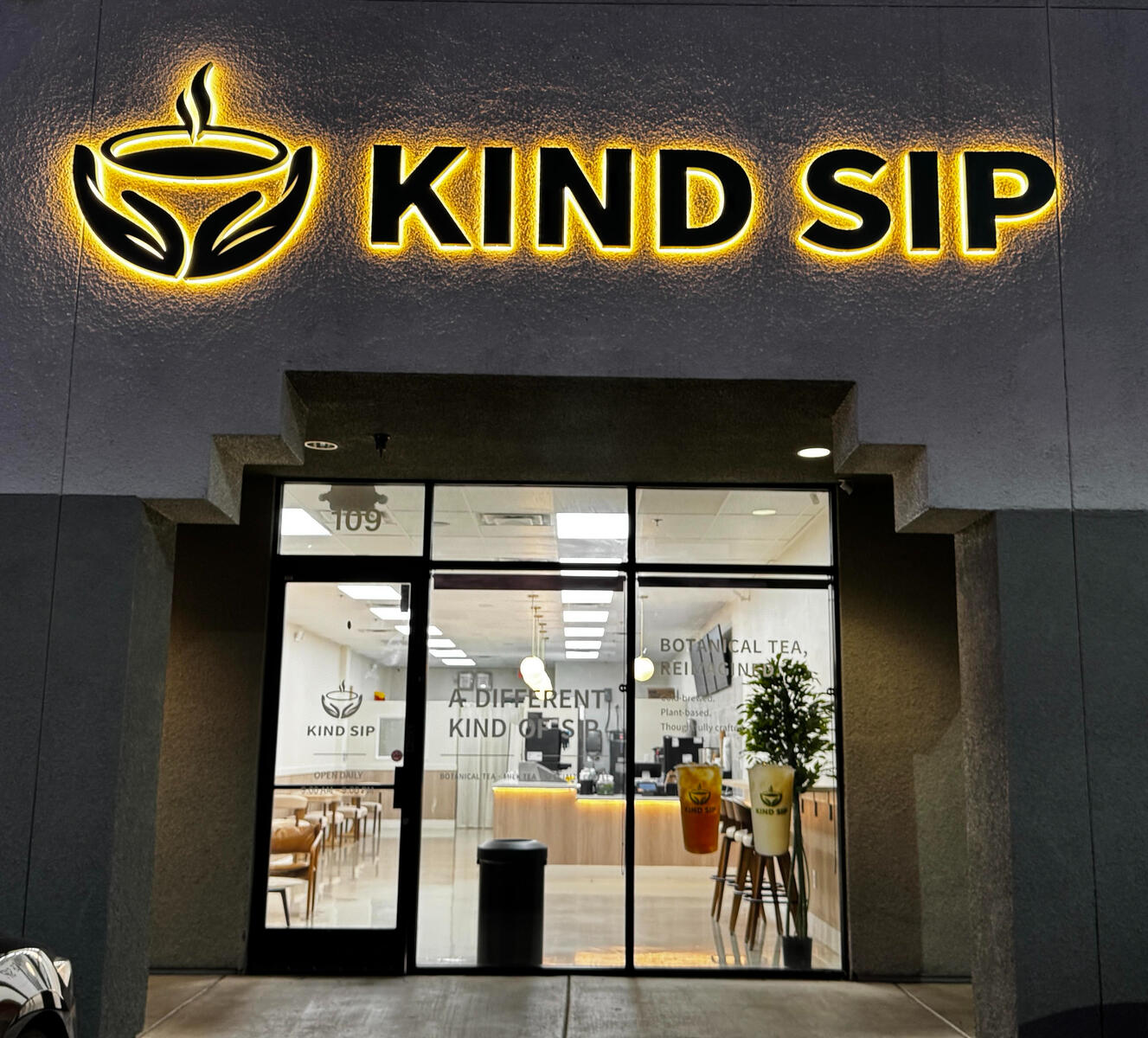 Kind Sip café storefront with an illuminated sign at night